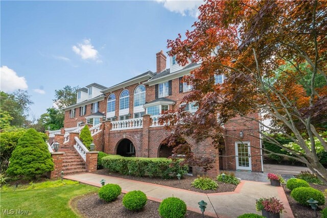 view of front of home featuring brick siding, a chimney, and stairs