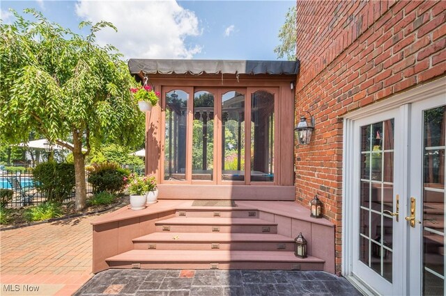 exterior space with brick siding, fence, and french doors