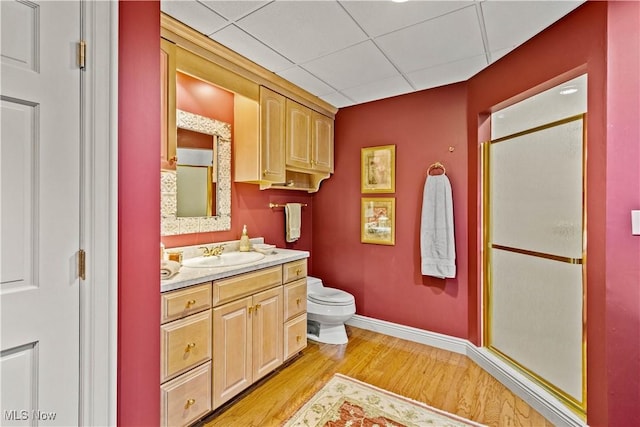 bathroom featuring vanity, toilet, baseboards, a shower stall, and wood finished floors