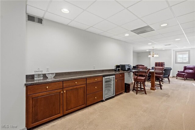 kitchen with visible vents, dark countertops, beverage cooler, open floor plan, and light colored carpet