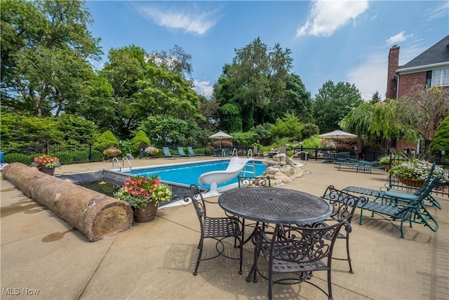 pool featuring fence, a water slide, and a patio