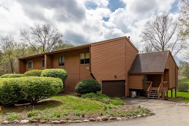 view of side of home with a garage, aphalt driveway, and roof with shingles