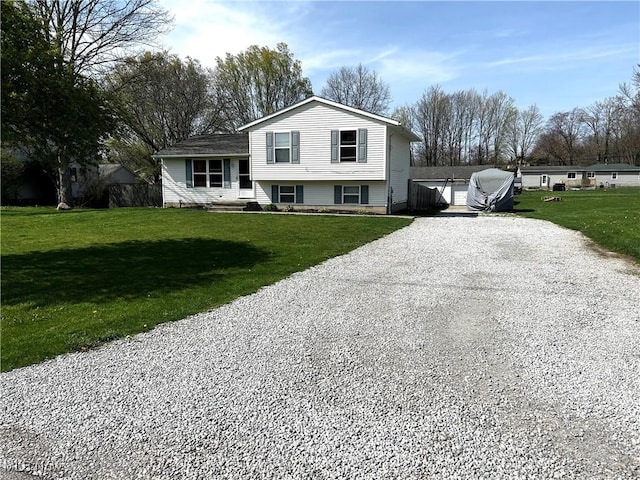 tri-level home with gravel driveway and a front yard