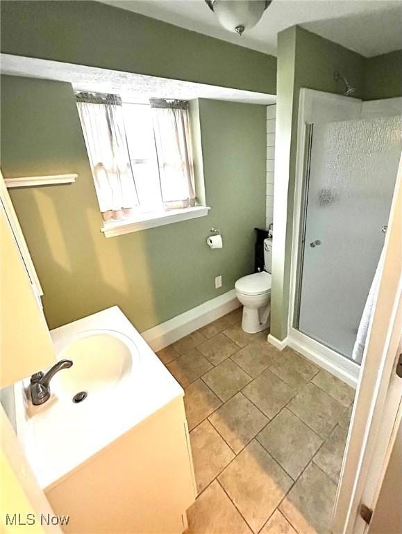 full bathroom featuring tile patterned flooring, vanity, toilet, baseboards, and a stall shower