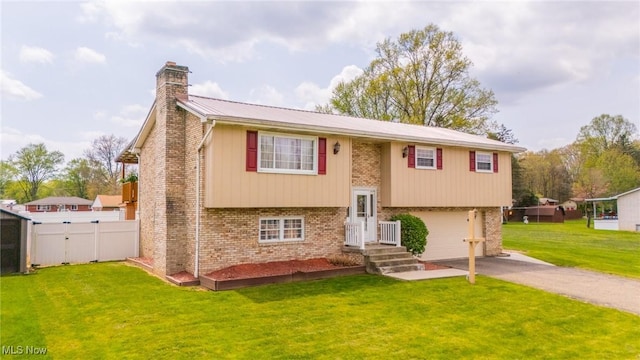 split foyer home with brick siding, an attached garage, aphalt driveway, and a chimney