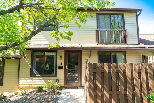 rear view of property featuring fence and a balcony