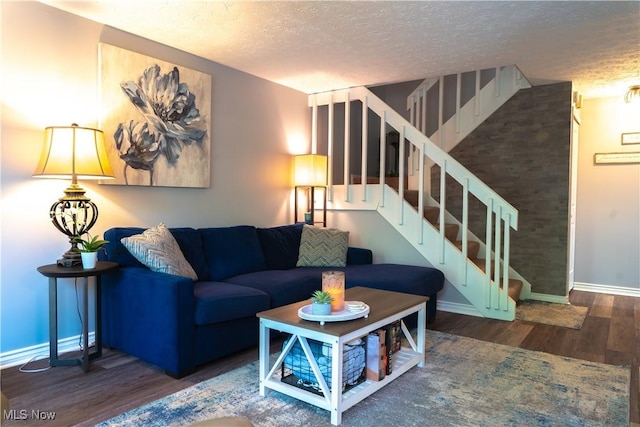 living room with stairway, baseboards, a textured ceiling, and wood finished floors