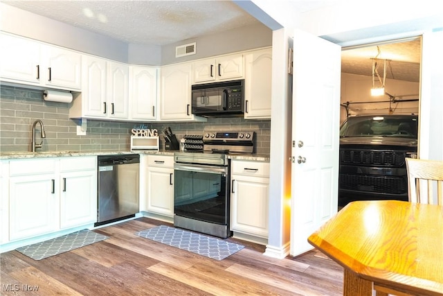 kitchen with white cabinets, a sink, stainless steel appliances, decorative backsplash, and visible vents