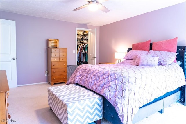 bedroom with a closet, a walk in closet, a ceiling fan, and carpet flooring