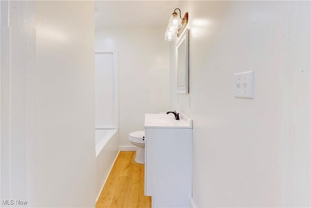full bath featuring toilet, baseboards, wood finished floors, and vanity