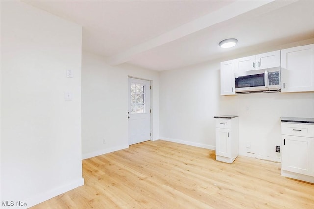 kitchen with light wood-style floors, baseboards, white cabinets, and dark countertops