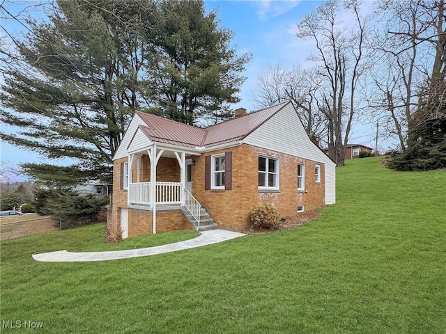 bungalow with brick siding, a front lawn, a chimney, and metal roof