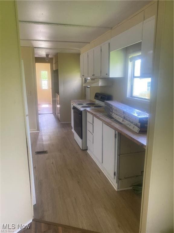 kitchen featuring white cabinets, white electric range oven, a wealth of natural light, and light wood-style flooring