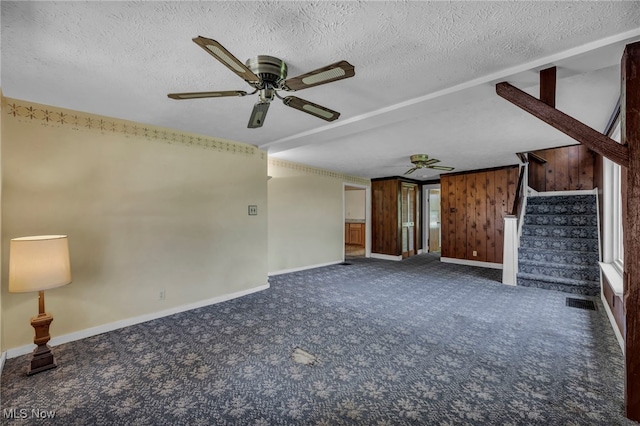 unfurnished living room featuring carpet floors, baseboards, stairway, a textured ceiling, and a ceiling fan