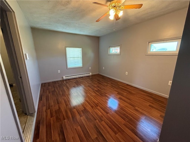 empty room with a ceiling fan, a baseboard heating unit, plenty of natural light, and wood finished floors