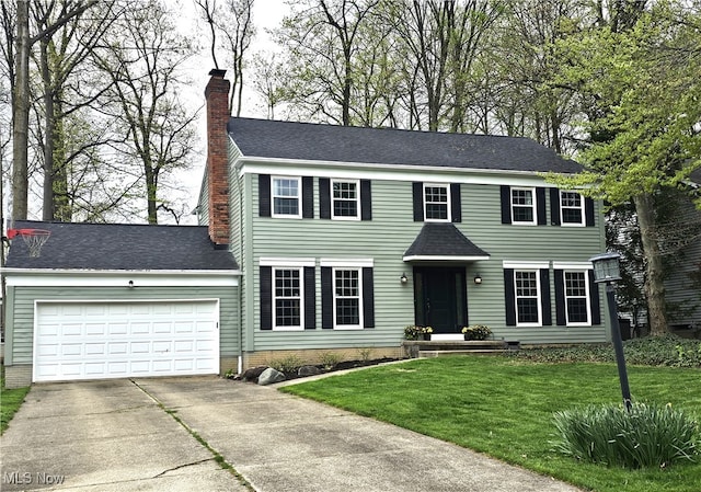 colonial-style house featuring a garage, a chimney, driveway, and a front lawn