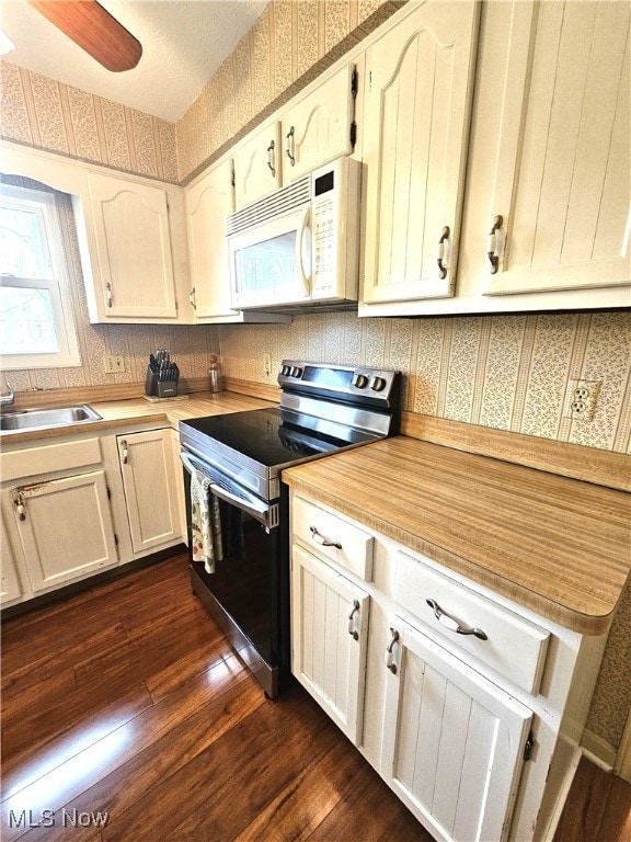 kitchen featuring electric stove, white microwave, and wallpapered walls