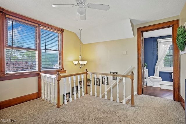 corridor featuring baseboards, carpet, a chandelier, and an upstairs landing