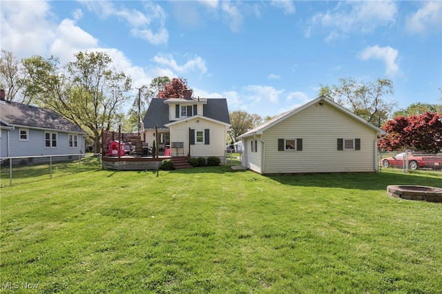 back of property with a fenced backyard, a yard, a fire pit, and a deck