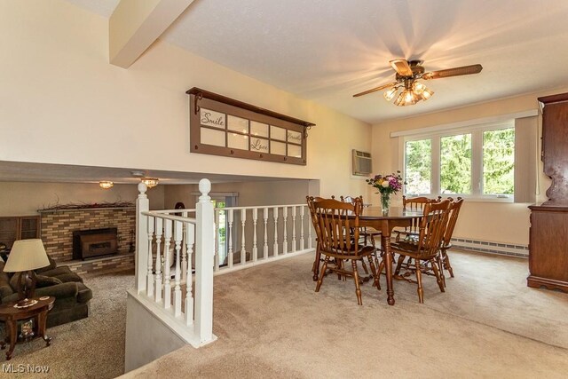 dining space with a ceiling fan, carpet, a brick fireplace, and a baseboard heating unit