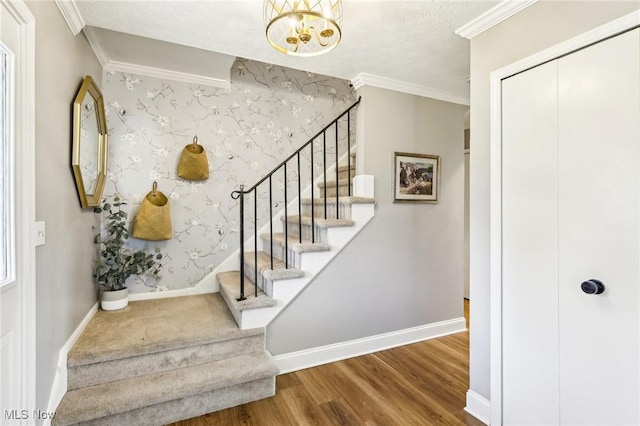 stairs featuring crown molding, baseboards, a chandelier, and wood finished floors
