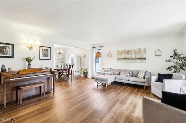 living area featuring an inviting chandelier, crown molding, and wood finished floors