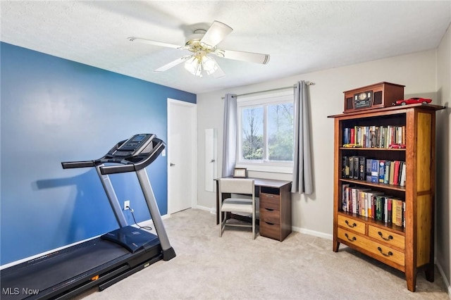 workout room featuring baseboards, ceiling fan, light carpet, and a textured ceiling