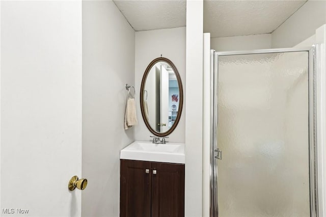 bathroom with vanity, a shower stall, and a textured ceiling