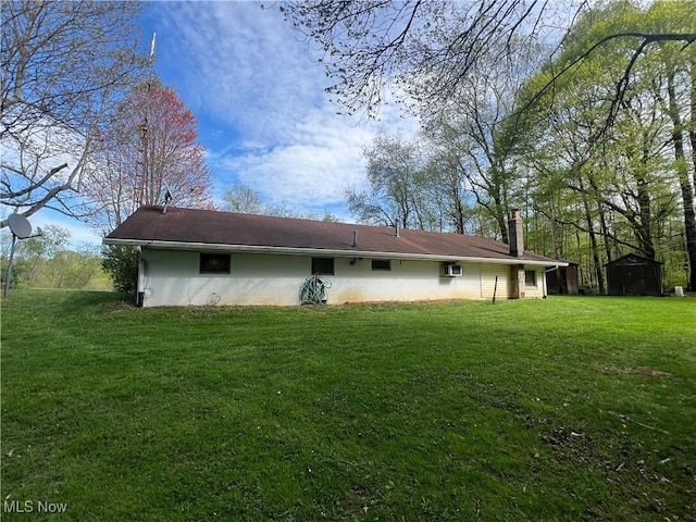 rear view of property with a lawn, an outdoor structure, a storage shed, and a chimney