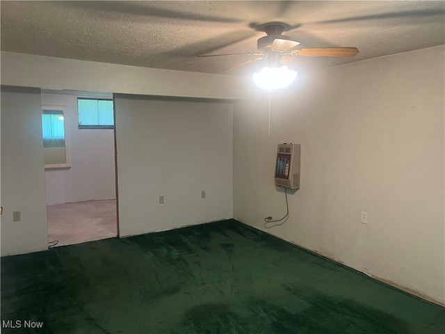 basement featuring carpet floors, a ceiling fan, heating unit, and a textured ceiling
