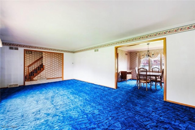 unfurnished living room with an inviting chandelier, carpet, visible vents, ornamental molding, and stairway