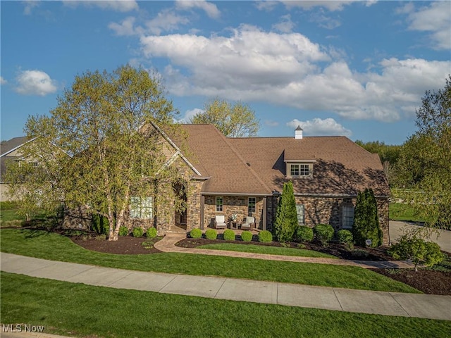view of front of home with stone siding, an outdoor living space, and a front yard