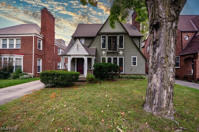 view of front of property featuring stucco siding, a chimney, and a front lawn