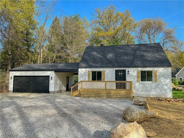 new england style home featuring a garage, a shingled roof, and driveway