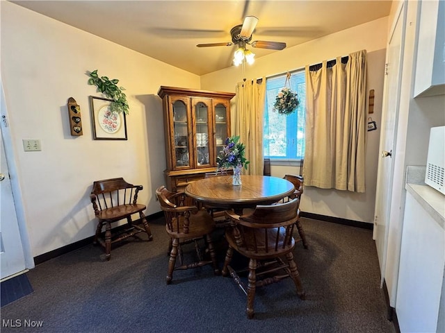 carpeted dining space with ceiling fan, vaulted ceiling, and baseboards