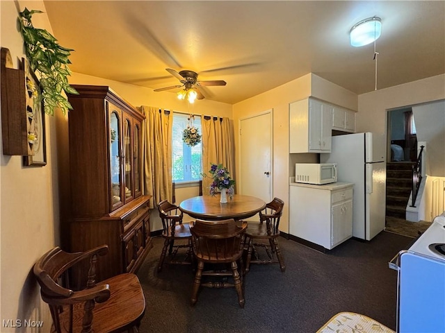 dining area with ceiling fan and dark colored carpet