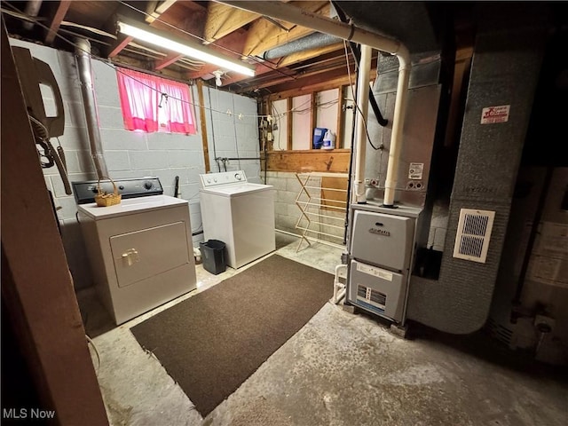 clothes washing area featuring washer and dryer, laundry area, and heating unit