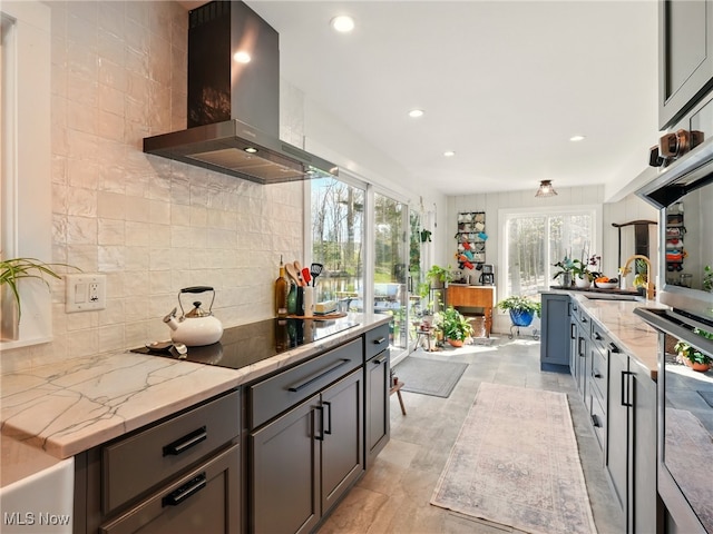 16165 Thompson Rd, Thompson, OH 44086 - kitchen featuring wall chimney range hood, black electric cooktop, tasteful backsplash, light stone counters, and recessed lighting