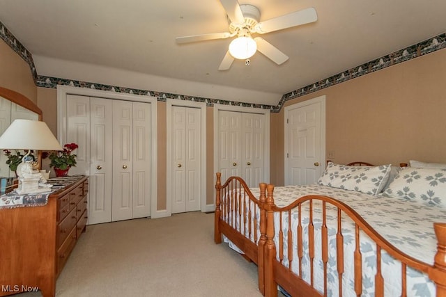 bedroom with multiple closets, light carpet, and a ceiling fan