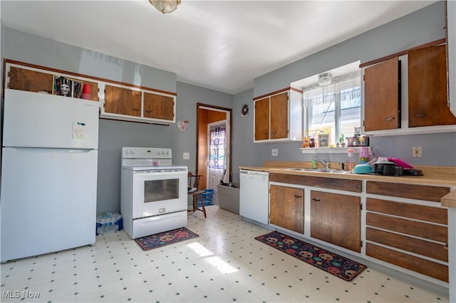 kitchen with a sink, light floors, brown cabinets, and white appliances