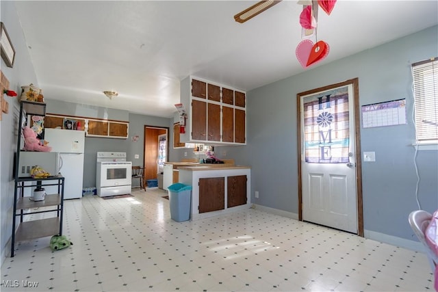 kitchen with brown cabinets, white appliances, a peninsula, baseboards, and light floors