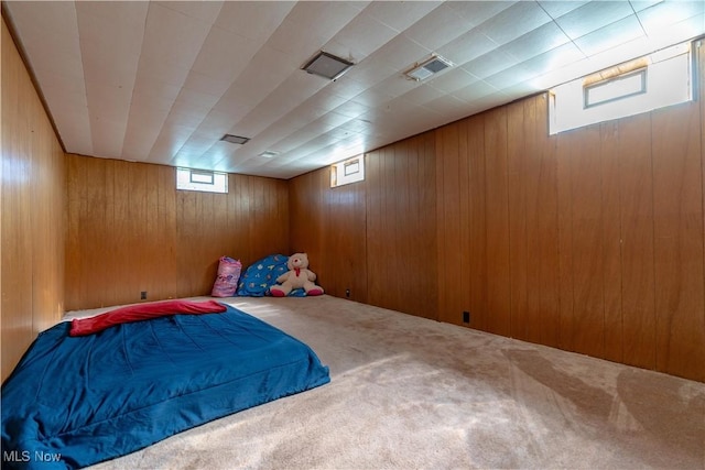 unfurnished bedroom with wooden walls, carpet floors, and visible vents
