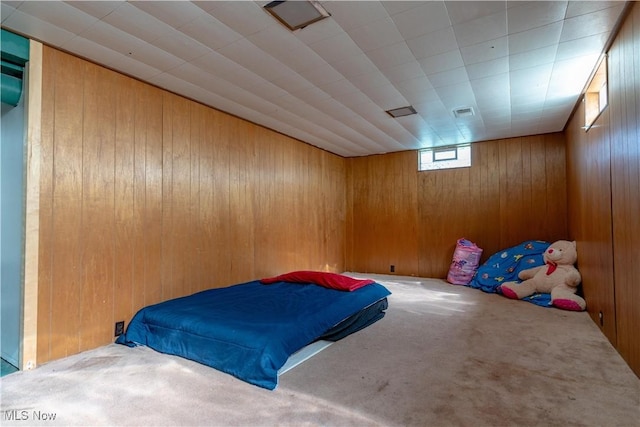 unfurnished bedroom with visible vents, wood walls, and carpet
