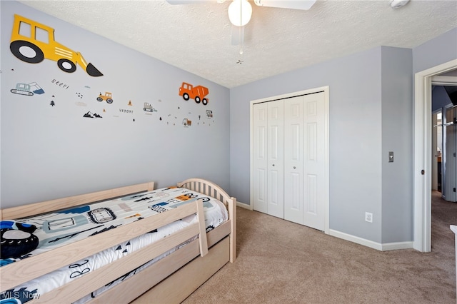 bedroom with ceiling fan, a textured ceiling, carpet floors, baseboards, and a closet