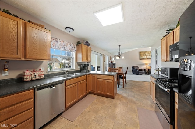 kitchen with dark countertops, open floor plan, black appliances, a sink, and a notable chandelier