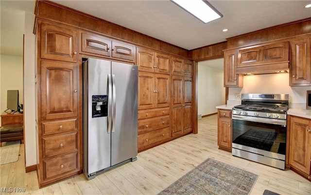 1423 N Wooster Ave, Dover, OH 44622 - kitchen with brown cabinets, light countertops, light wood-style flooring, stainless steel appliances, and under cabinet range hood