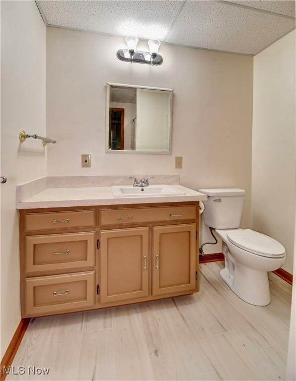 1423 N Wooster Ave, Dover, OH 44622 - bathroom featuring vanity, toilet, baseboards, a drop ceiling, and wood finished floors