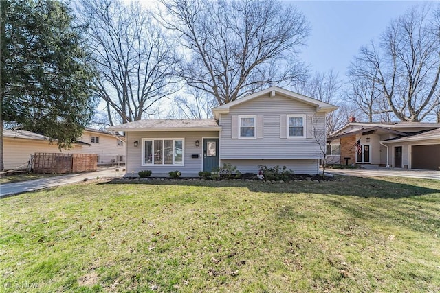 tri-level home featuring fence and a front lawn