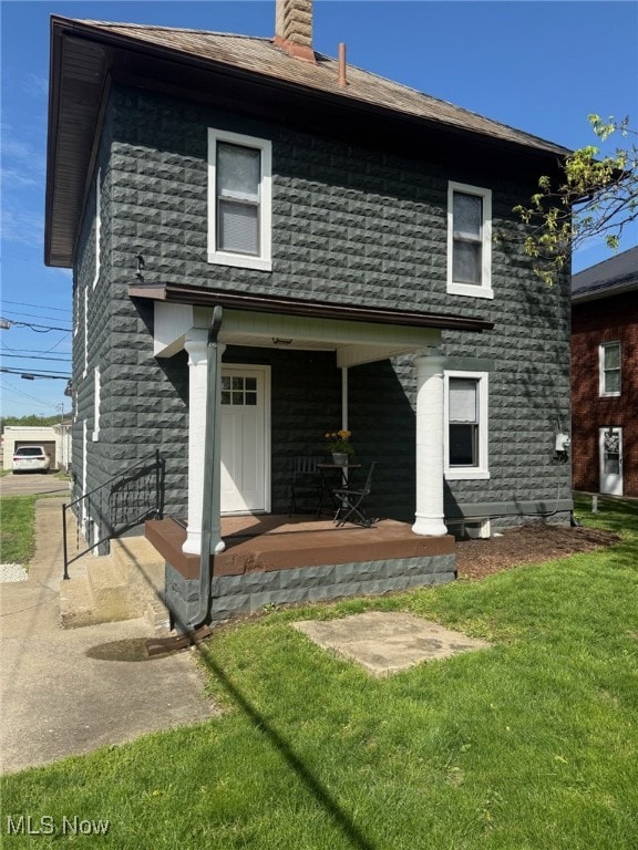 view of front facade featuring a porch, a chimney, and a front yard