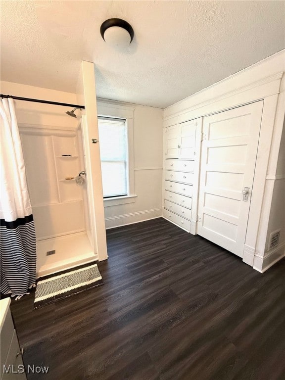 unfurnished bedroom featuring a textured ceiling, dark wood-style floors, and baseboards
